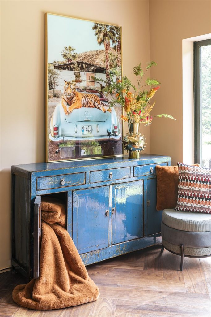 buffet en bois repeint en bleu, un plaid sort de ce buffet. 